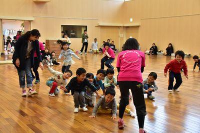 子どもたちが床に手をついたり、しゃがんだりしていて、女性スタッフと遊んでいる写真