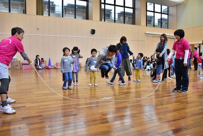 グレーのパーカーをきた男の子が大きくジャンプして大繩を飛んでいる写真