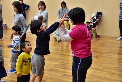 ピンク色のシャツを着ているスタッフと両手でハイタッチをしている男の子の写真
