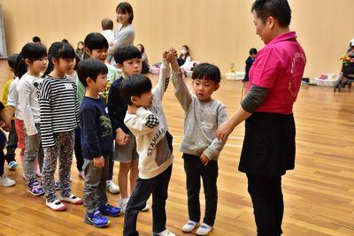 子供たちが2列に並び、先頭の男の子2人が繋いだ手を挙げている写真