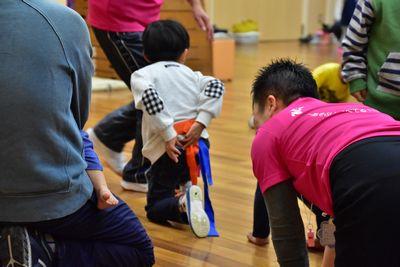 男の子がオレンジ色のはちまきを腰に付けようとしている写真