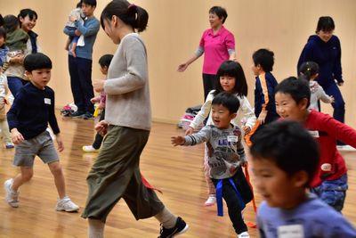 腰に付けた女性のはちまきを取ろうと女性を追いかける子供たちの写真