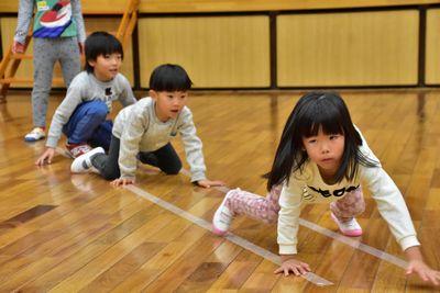 床に引かれた2本のラインの上を四つん這いになって進んでいる女の子と次の順番を待っている男の子たちの写真