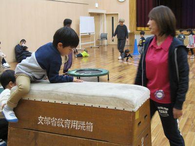 跳び箱によじ登っている男の子の写真