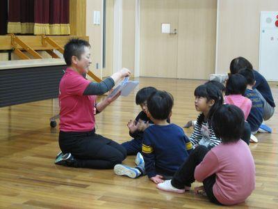 指導者の周りに集まって座っている子供たちの写真