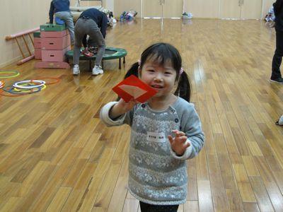 折った折り紙を見せてくれている小さな女の子の写真