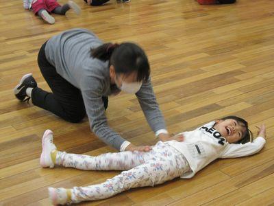 女の子が寝転んでお母さんが体を揺らしている写真