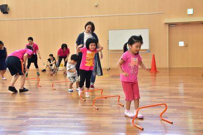 小さなオレンジ色のハードルを飛び越えようとしている女の子の写真