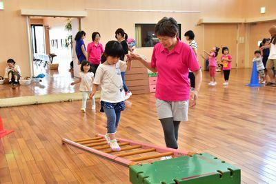 箱に立てかけられてた梯子の上を歩いている女の子の手を引いている女性の写真