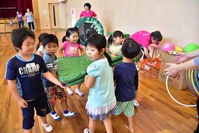 使ったマットを畳んで運んでいる子供たちの写真