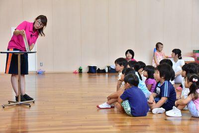 絵本の読み聞かせをしているスタッフの女性と座って聞いている子供たちの写真
