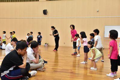親と子供に分かれてそれぞれ横一列に並び、親は床に座り子供は立って向かい合っている写真