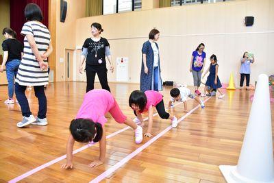 四つん這いになって歩いている子供たちと傍で見ている母親の写真