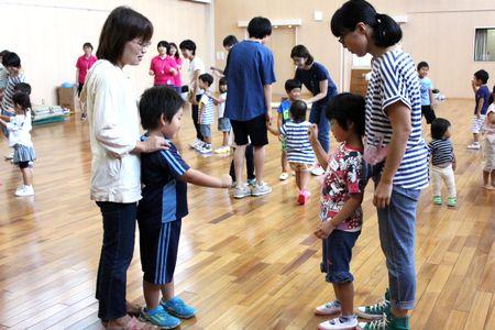 二組の親子が向かい合って立ち、子供同士がじゃんけんをしている写真