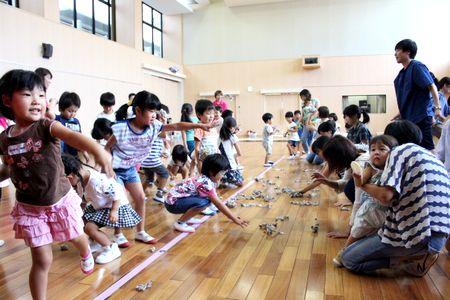 線を挟んで向かい合って立ち、相手チームの陣地に向かって丸めた新聞紙を投げ込んでいる子供たちの写真