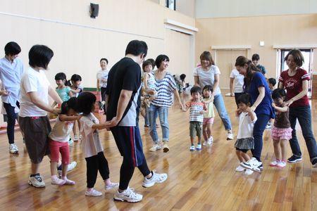 縦一列に並んで前の人の肩に手を置いて歩いている親子の写真