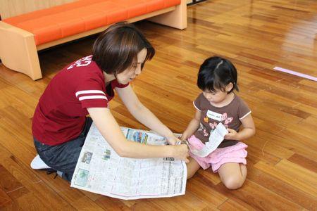 新聞紙を細長くちぎっている母親と女の子の写真