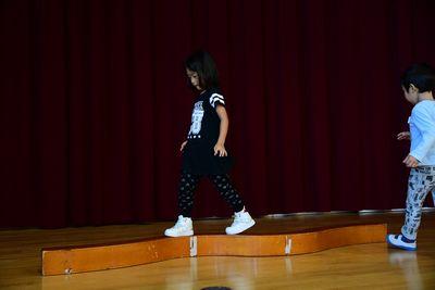 平均台のように長くのびた木の上を女の子が歩いている写真