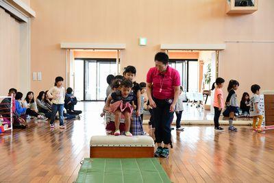 一段の跳び箱の上に小さな女の子が立っていて、飛び降りようとしている写真