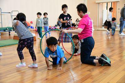 スタッフが持っている輪っかの中を子供たちがくぐり抜けている写真