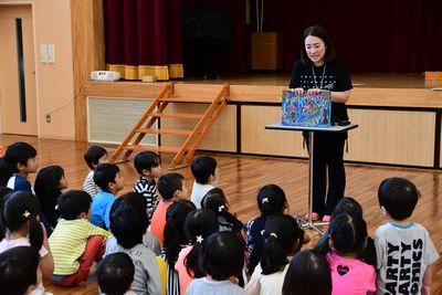 スタッフの女性が子供たちに絵本の読み聞かせをしている写真