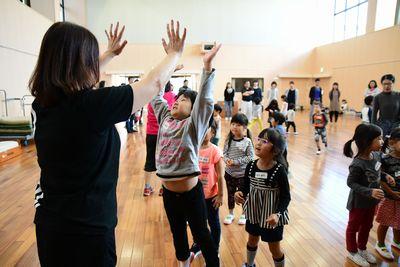 子どもたちが並んでいて、スタッフの女性と順番にハイタッチをしている写真