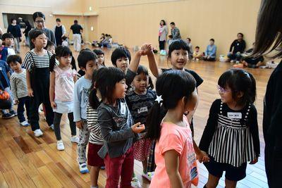 子どもたちが縦に2列に並んでいて、二人の女の子が繋いだ手を上に上げてみんなに見せている写真