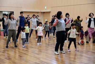 親子が一緒にエビカニクスのダンスを踊っており、両手ピースサインででカニのハサミを作っている写真