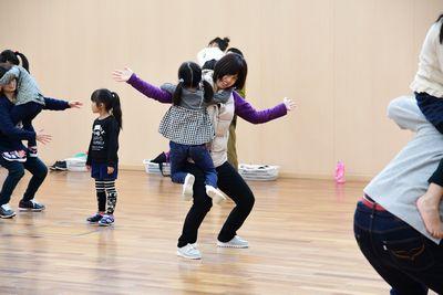 両手を広げて足を曲げた体勢のお母さんに、女の子が抱きついている写真