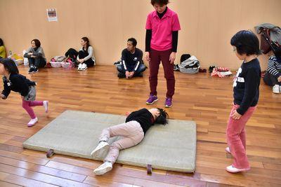 マットの上を寝転がって進んでいる子供の写真
