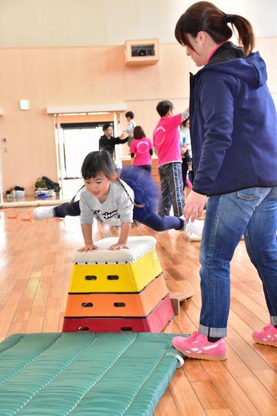 3段の跳び箱を大きく足を広げて飛んでいる女の子の写真