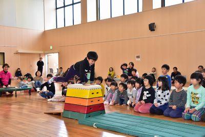 男の子の跳び箱のお手本を座って見ている子供たちの写真