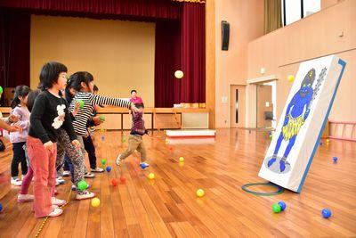 青鬼のボードに向かってカラーボールを投げている子供たちの写真