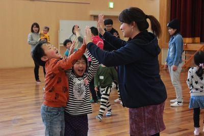 女性の保護者と子供たちがハイタッチをしている写真