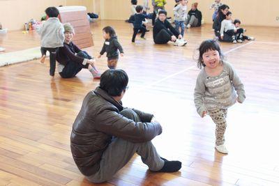 体育座りをしている保護者の周りを走っている子供たちの写真
