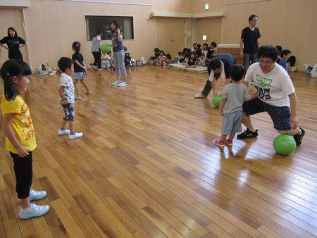 親子で間をあけて向かい合って立っており、緑色のボールをそれぞれの親子のお父さん、お母さんが持っている写真