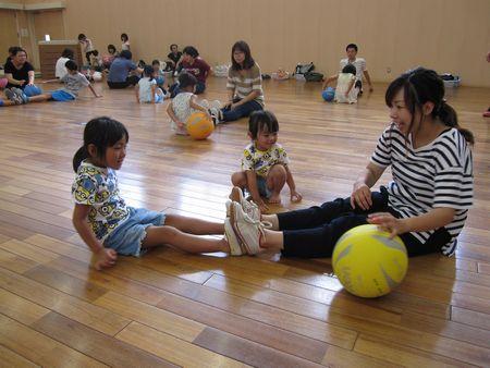 女の子とお母さんが床に向かい合って座って足の裏を合わせている写真