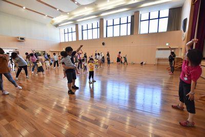 体育館で親子がラジオ体操をしている写真