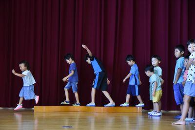 バランスを取りながら、細い木の上を歩く子供たちの写真