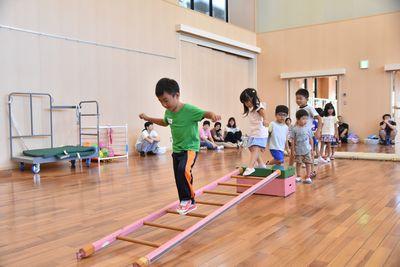 跳び箱からかけられた木のはしごを渡る子供たちの写真