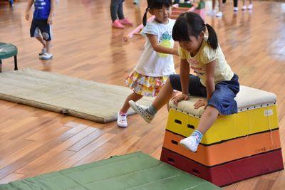 3段の跳び箱にお尻をつけて、飛び越えようとする女の子の写真