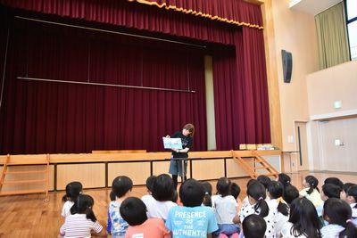 並んで座っている親子の前で、女性が読み聞かせをしている写真