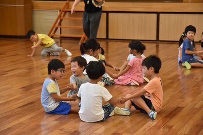 手をつなぎ、輪になって座る子供たちの写真