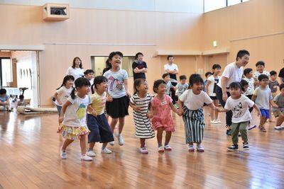 7人の女の子が、手をつないで横に並び、ジャンプをしている写真