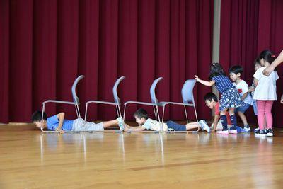 4客の椅子が繋がって置かれており、椅子の脚の間を子ども達が床に這いながら通っている写真