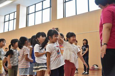 子ども達が2人1組で手をつないでスタッフの女性の前に1列に並んでおり、先頭の女の子二人が、つないだ手を上に挙げて笑顔で写っている写真