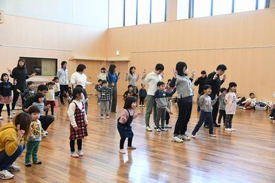 両手でカニさんポーズをして、エビカニクスを踊る親子の写真