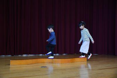 細長い木の上を渡る男の子と女の子の写真