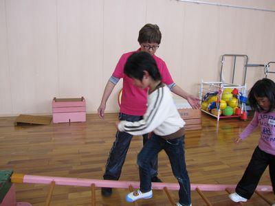 バランスを取りながら、木のはしごを渡る男の子と、女の子の写真