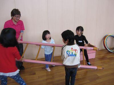 女性スタッフと、4人の子供が木のはしごを運んでいる写真
